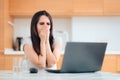 Worried Woman Reading the News at Home in the Kitchen