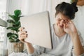 Sad girl crying from bad news from tablet while sitting home in during quarantine. Young woman lost her job, depressed, worried