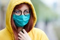 A sad girl with glasses in a reusable medical blue mask looks away warily Royalty Free Stock Photo