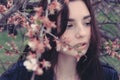 Sad girl hiding in cherry flower branches