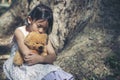 Sad girl hugging teddy bear sitting under tree sadness alone in green park. Lonely girl feeling sad unhappy sit outdoors hug best Royalty Free Stock Photo