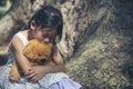 Sad girl hugging teddy bear sitting under tree sadness alone in green park. Lonely girl feeling sad unhappy sit outdoors hug best Royalty Free Stock Photo