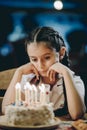 Sad girl looking at her birthday candles or making her birthday wish Royalty Free Stock Photo