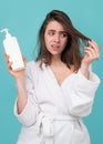 Sad girl looking at her damaged hair. Woman hold bottle shampoo and conditioner. Woman touching her hair, hair loss or Royalty Free Stock Photo