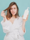 Sad girl looking at her damaged hair. Woman hold bottle shampoo and conditioner. Woman touching her hair, hair loss or Royalty Free Stock Photo