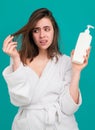 Sad girl looking at her damaged hair. Woman hold bottle shampoo and conditioner. Woman touching her hair, hair loss or Royalty Free Stock Photo