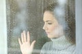 Sad girl looking through a window in a rainy day