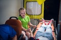 Sad girl looking at the woman lying on a stretcher in an ambulance car, the girl is holding her sister`s hand Royalty Free Stock Photo