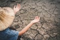 Sad girl praying for the rain on cracked dry ground