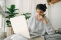 Sad girl reading bad news from laptop, sitting home alone during quarantine. Young woman worries about losing job, depression.