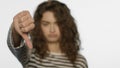 Sad girl showing thumbs down in studio. Upset woman showing dislike sign hand Royalty Free Stock Photo