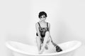 Sad girl sitting with fishnet stocking on leg on bathtub Royalty Free Stock Photo