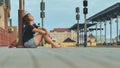 Sad girl sitting on the tiles of the railway station and crying. Royalty Free Stock Photo