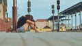 Sad girl sitting on the tiles of the railway station and crying. Royalty Free Stock Photo