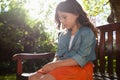 Sad girl sitting on wooden bench against plants Royalty Free Stock Photo