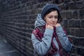 Sad girl stands near a brick wall in jacket hat and scarf Royalty Free Stock Photo