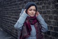 Sad girl stands near a brick wall in jacket hat and scarf Royalty Free Stock Photo