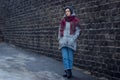 Sad girl stands near a brick wall in jacket hat and scarf Royalty Free Stock Photo