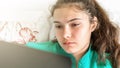 Sad girl teenager with ponytail looks at laptop screen Royalty Free Stock Photo