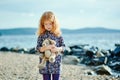 Sad girl with a toy is on the beach or lake Royalty Free Stock Photo