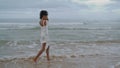 Sad girl walking ocean beach in white bikini on gloomy day. Thinking curly lady Royalty Free Stock Photo