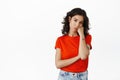 Sad and gloomy brunette woman looking with unamused, bored face at camera, standing uninterested and reluctant in red t