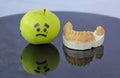 Sad green apple crying next to plaster model of lower teeth Royalty Free Stock Photo