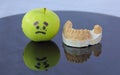 Sad green apple crying next to plaster model of lower teeth Royalty Free Stock Photo