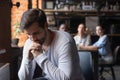 Sad guy sitting alone separately from other mates in cafe Royalty Free Stock Photo