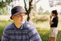 A sad guy is sitting on a park bench with a blurry unrecognizable girl in the background. A thoughtful person sits and looks into Royalty Free Stock Photo