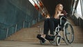 Sad helpless disabled young woman in front of the stairways in the wheelchair. inaccessible area Royalty Free Stock Photo