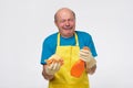 Sad hispanic senior man with cleaning equipment is tired of household chores. Royalty Free Stock Photo