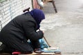 Sad homeless woman sitting on the street people passing by. Royalty Free Stock Photo