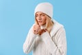 Sad ill woman in winter sweater and hat suffering from flu and cold, cough, isolated on blue studio background Royalty Free Stock Photo