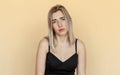 Sad and indifferent young woman with freckles, looking with boredom at camera, staring reluctant and upset, beige background