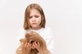 sad kid girl holds in hands cropped hair after cutting on a white background