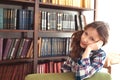 sad kid girl posing near book shelf at home. Royalty Free Stock Photo