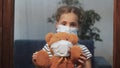 sad kid girl in protective medical mask by the window looks out. stay home pandemic coronavirus teddy bear concept. sad Royalty Free Stock Photo