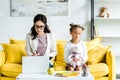 sad kid holding soft toy and sitting mother using laptop . Royalty Free Stock Photo