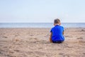 Sad kid sitting on empty beach alone Royalty Free Stock Photo