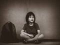 Sad Kid sitting on the floor with school bag waiting for parent. Royalty Free Stock Photo