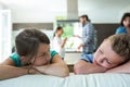 Sad kids leaning on sofa while parents arguing in background Royalty Free Stock Photo