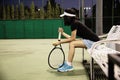 Sad lady tennis player sitting in the court after lose a match