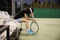 Sad lady tennis player sitting in the court after lose a match