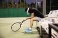 Sad lady tennis player sitting in the court after lose a match