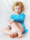 Sad little blonde curly sitting girl on the white