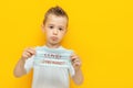 Sad little boy holding a medical mask with the inscription with a question Covid second wave Royalty Free Stock Photo