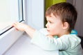 Sad little boy looks out the window. Portrait of Caucasian boy near window. Melancholic child. Royalty Free Stock Photo