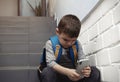 Sad little boy with mobile phone sitting on stairs Royalty Free Stock Photo