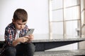 Sad little boy with mobile phone sitting on stairs Royalty Free Stock Photo